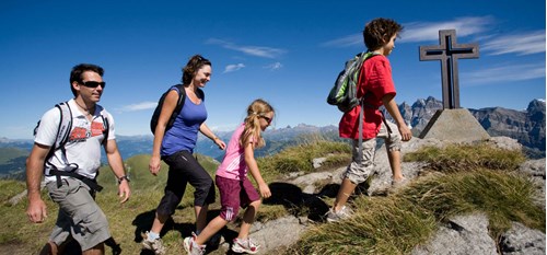 A family wearing summer clothes hiking to a summit against a blue sky