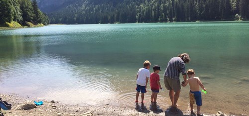 A woman and three kids paddling in tree lined Lac Montriond