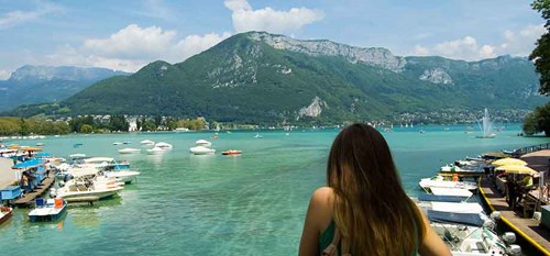 A woman with long hair looking out over a lake with mountains in the background