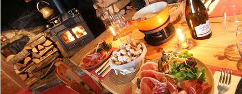 A table set for fondue with plates of meat, bread and salad